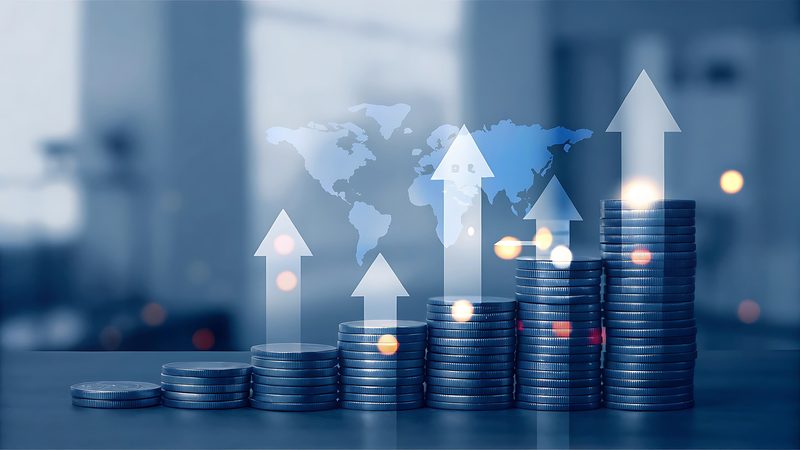 Stacks of coins with rising arrows over a translucent world map, representing transport cost analysis